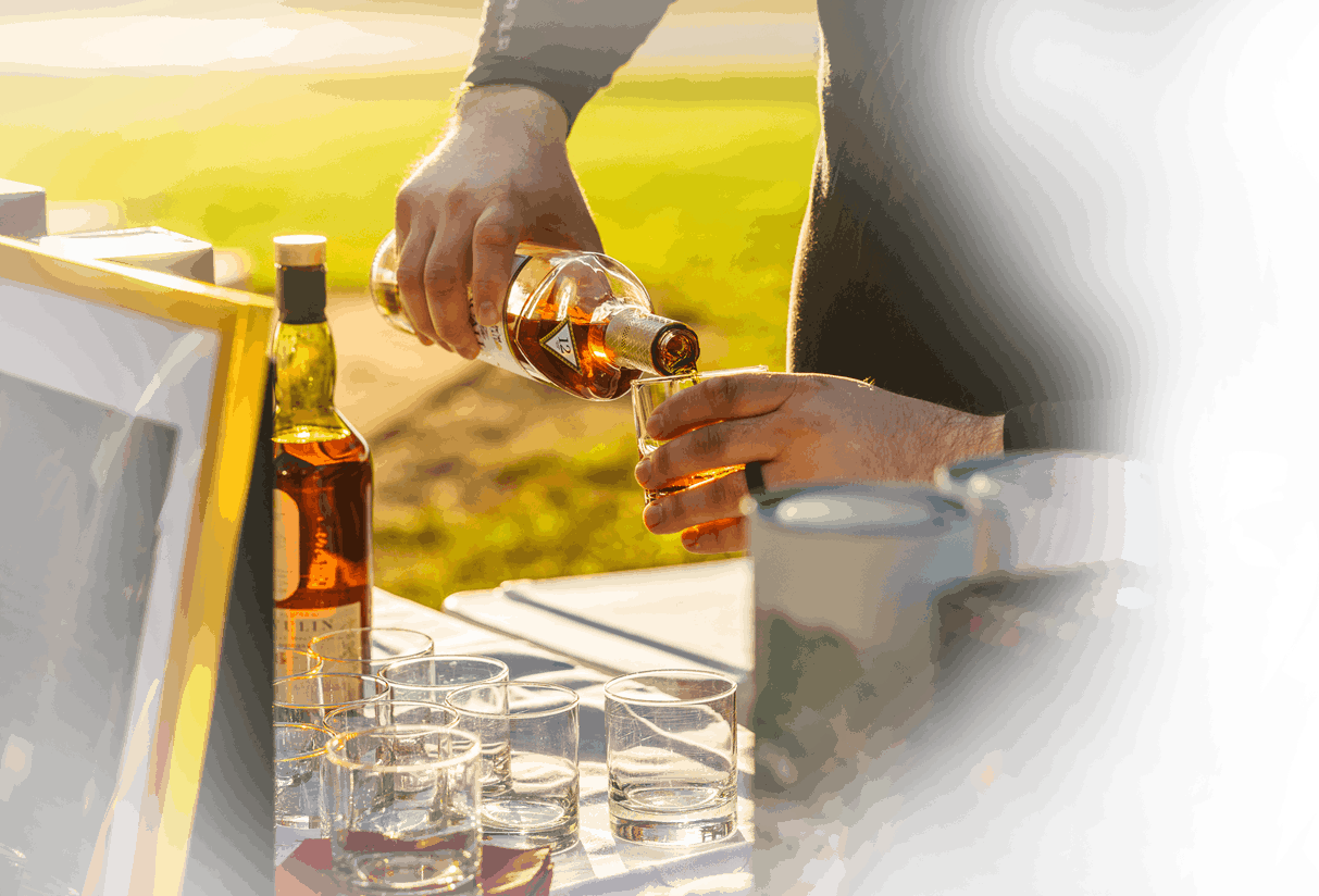 Man pouring alcohol in a glass at a catered event by Liquid Assets.